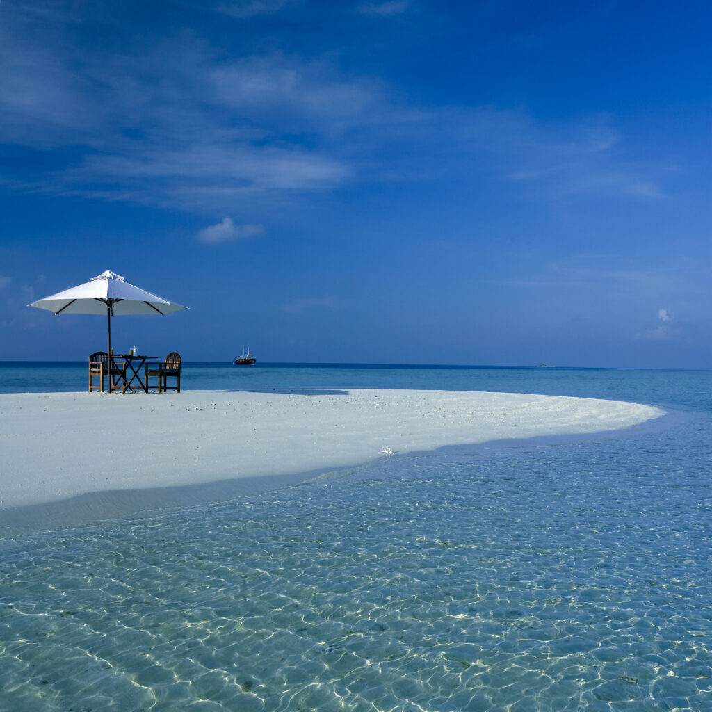 Tropisch strand met tafel en parasol, ideaal voor een luxe halalvakantie, aanbevolen door Halalvakantiegids.nl.