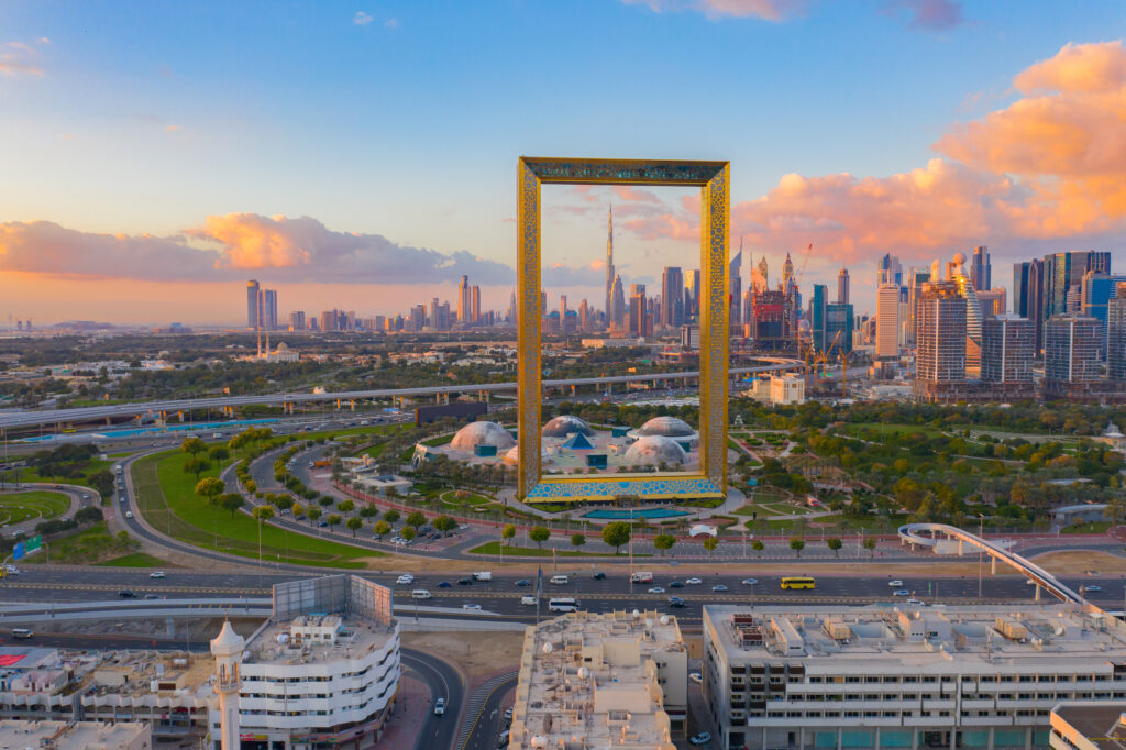 De Dubai Frame bij zonsondergang met uitzicht op de moderne skyline van Dubai, een populaire halal vakantiebestemming.