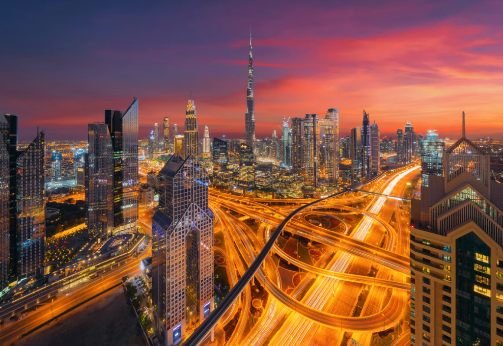 Skyline van Dubai Downtown bij zonsondergang met de Burj Khalifa en verlichte snelwegen, een top halal vakantiebestemming in de VAE.