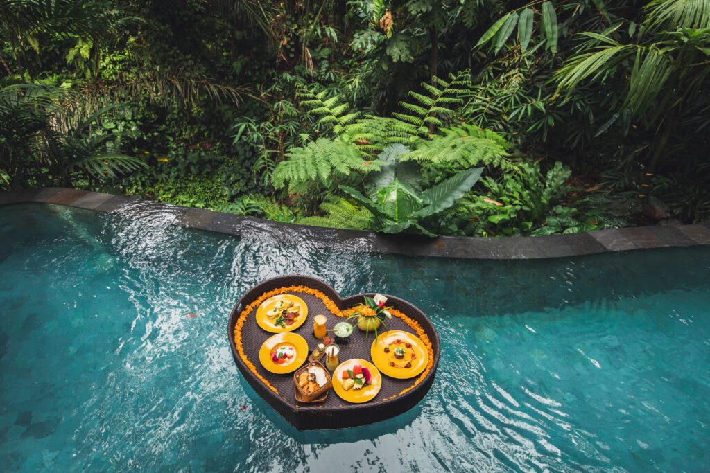 Een luxe floating breakfast in een hartvormige mand in een zwembad, omgeven door tropische jungle in Bali, Indonesië.