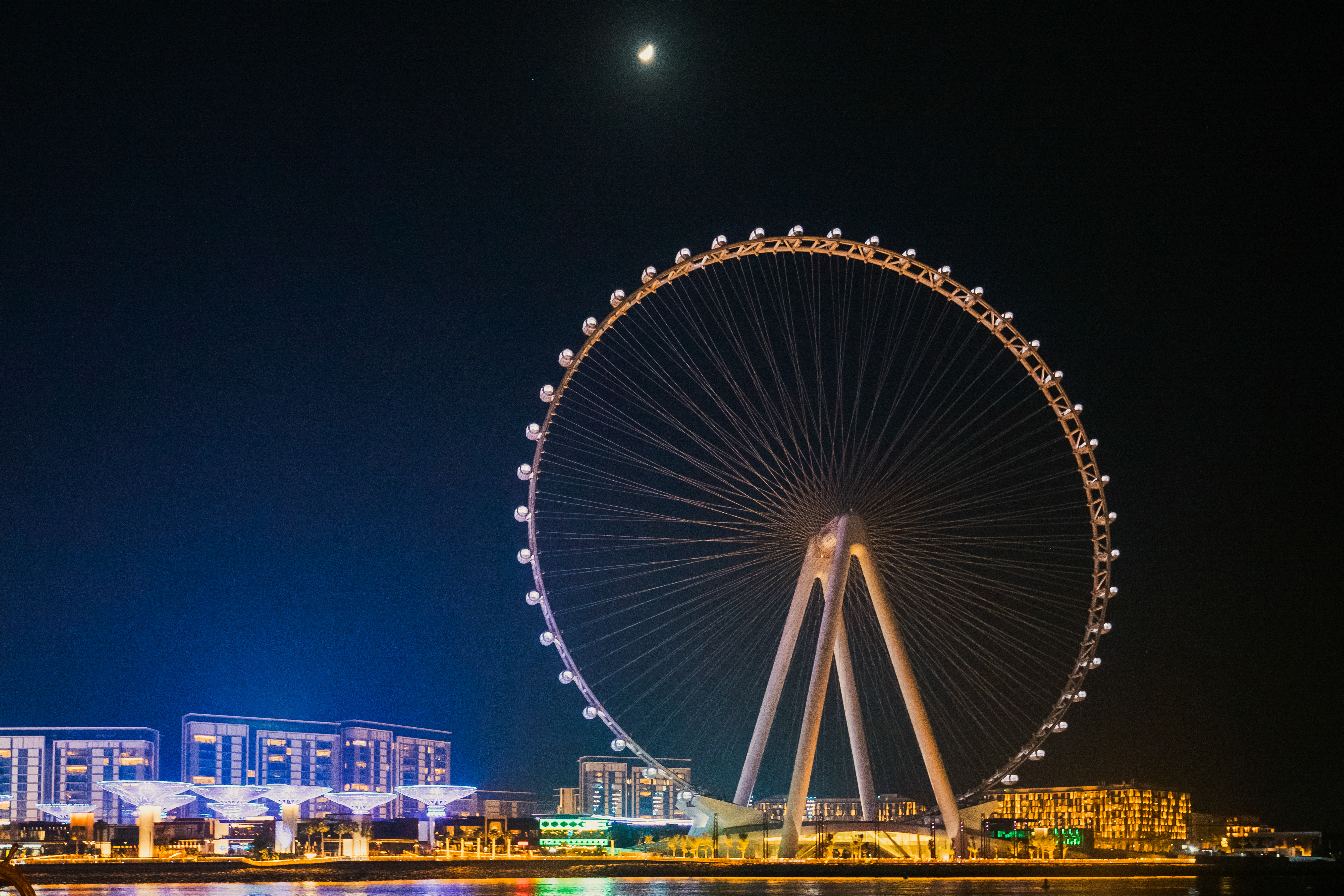 Ain Dubai, het grootste reuzenrad ter wereld, verlicht 's nachts met moderne gebouwen op de achtergrond.