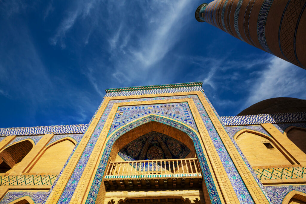 Islamitisch bouwwerk met kleurrijke mozaïektegels en een hoge poort, afgezet tegen een heldere hemel.