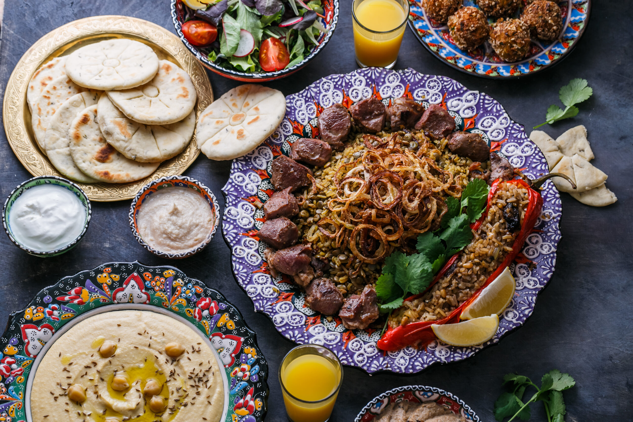 Halalmaaltijd met rijst, vlees, humus en vers brood, geserveerd op kleurrijke borden voor een all inclusive halalervaring.