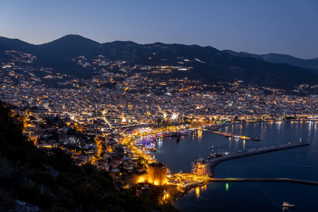 Nachtelijk uitzicht op Alanya, Turkije, met schitterende stadslichten en de haven.